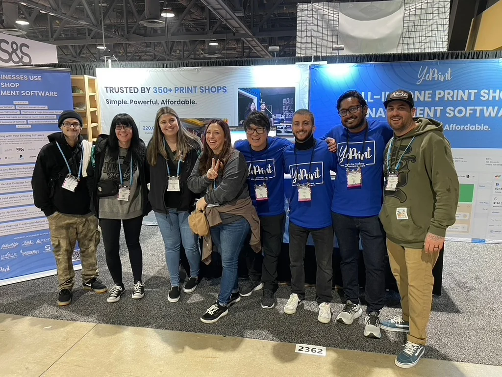 The YoPrint team, most in blue YoPrint shirts, together at the YoPrint trade-show booth.