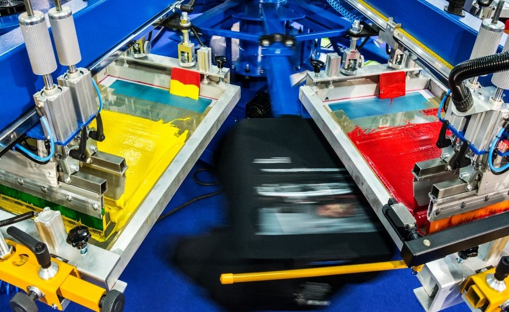 A t-shirt is on a pallet of an automatic screen printing machine and is moving between stations.
