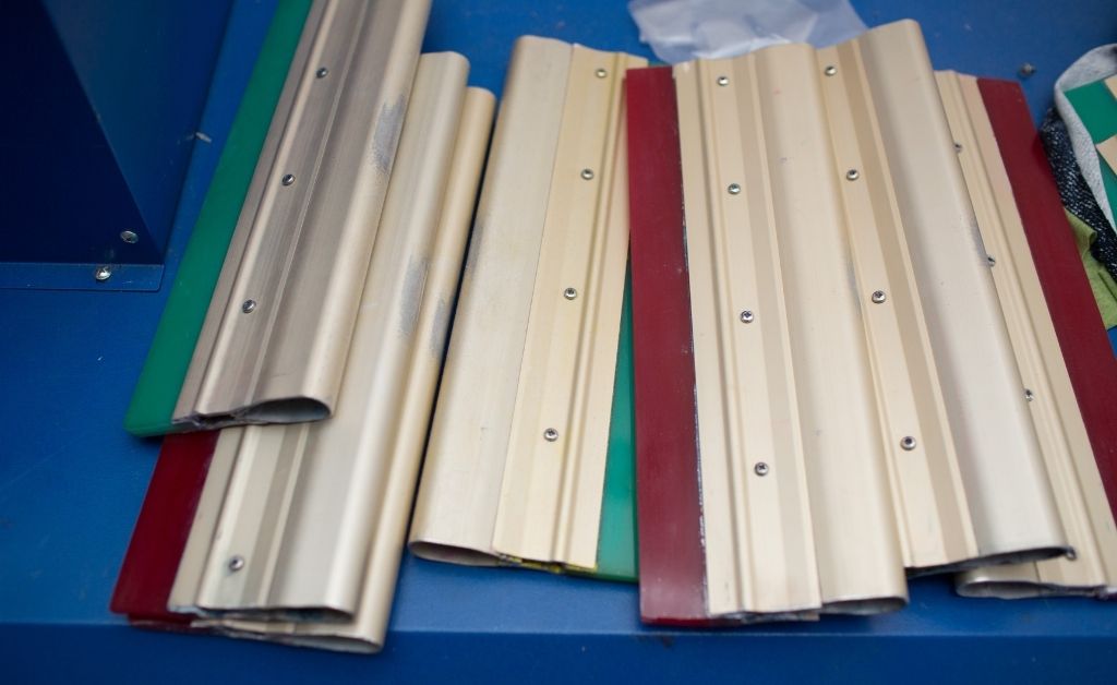 Squeegees with green and red blades laying on top of each other.