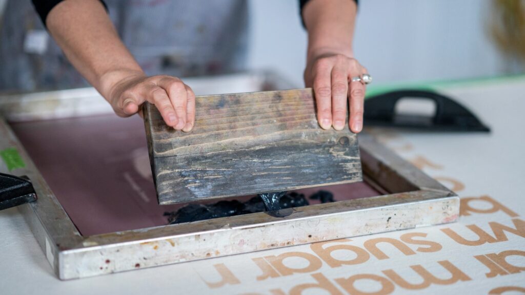 A person using a squeegee to screen print