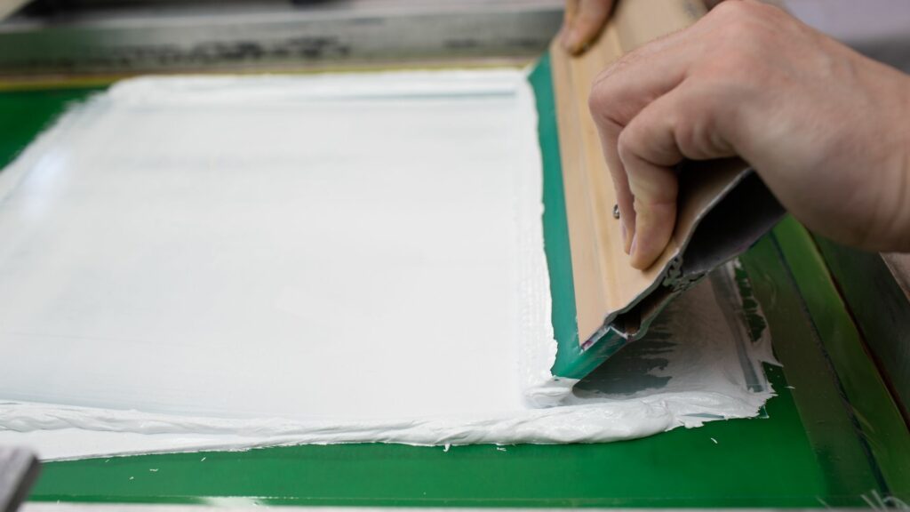 A person using a squeegee for screen printing