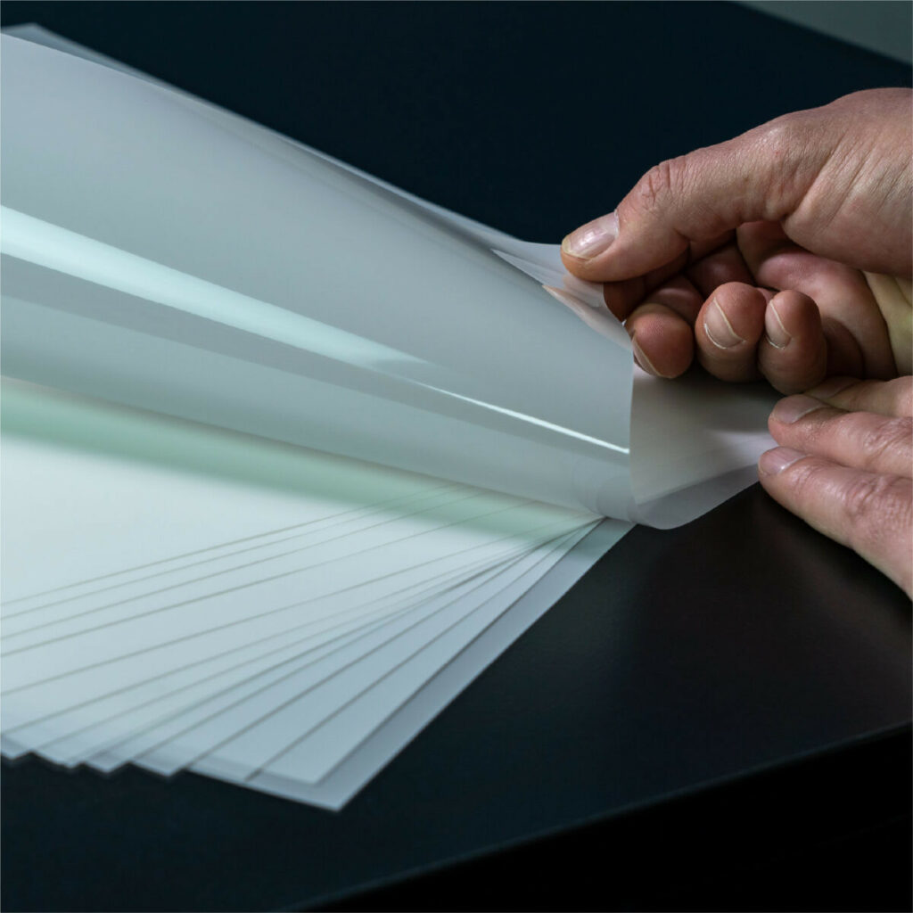 A person holding a small stack of DTF transfer films