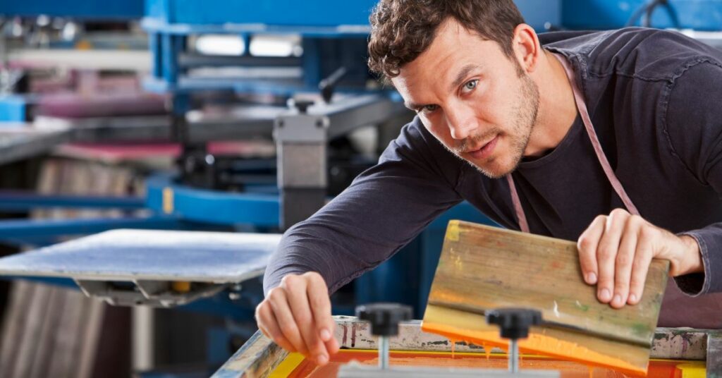 A man using a screen printing press