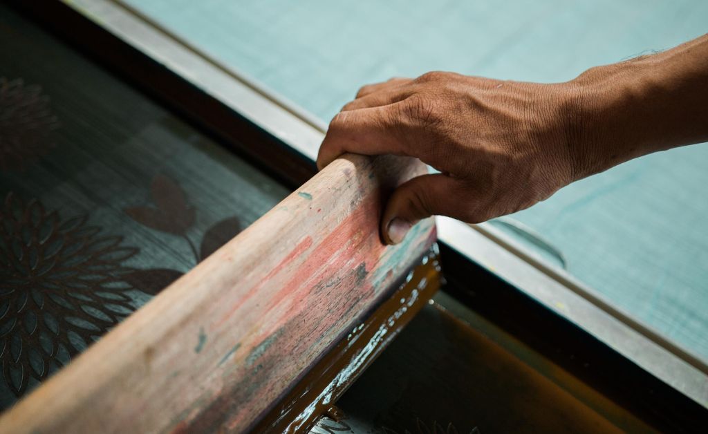 A man using a squeegee for screen printing