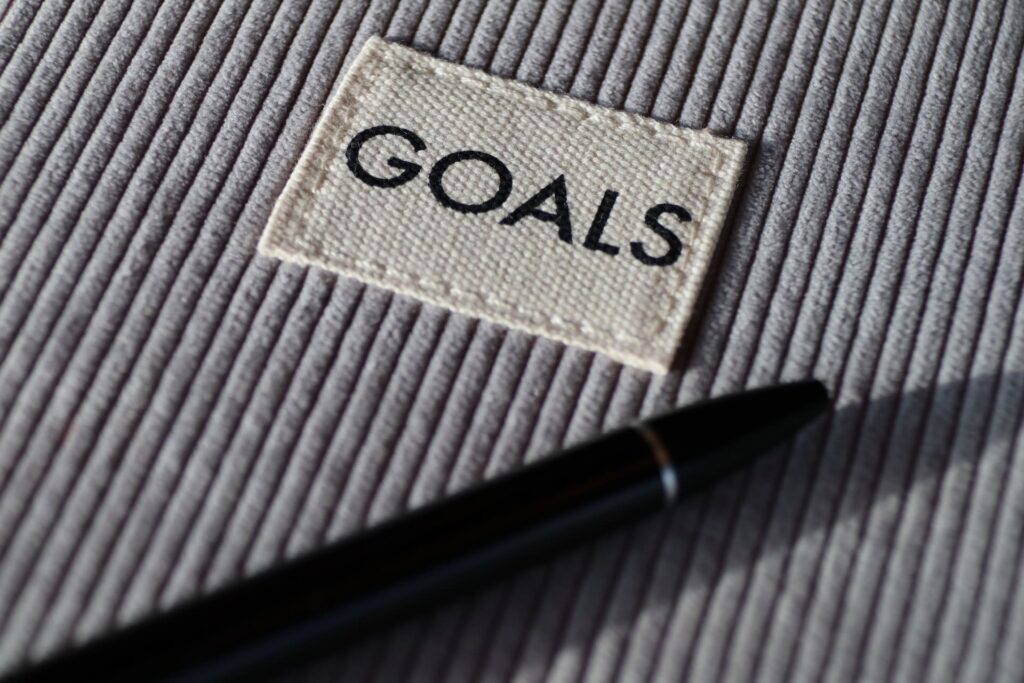 A book cover with the word "Goals" and a pen resting atop