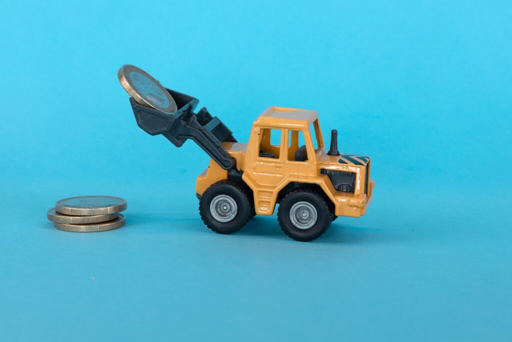 A toy excavator carrying some coins