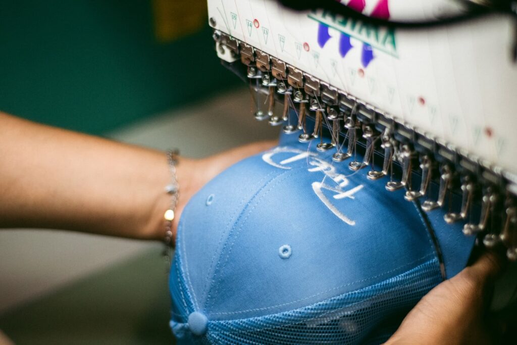 A person embroidering a hat with a multi-needle machine