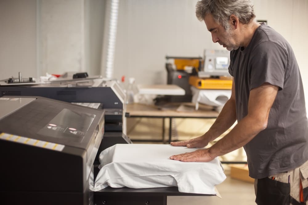 A man preparing a shirt on a DTG printer's platen