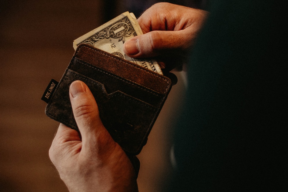 A man pulling out some dollar bills from his wallet