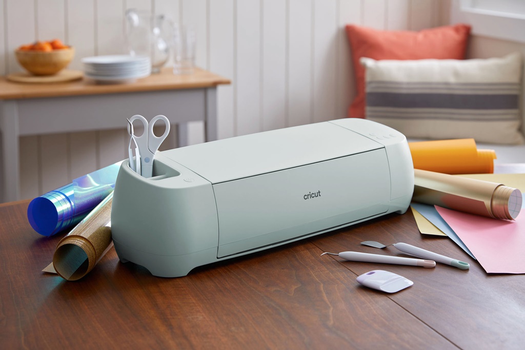 A Cricut cutter sits on top of a table with assorted stationery
