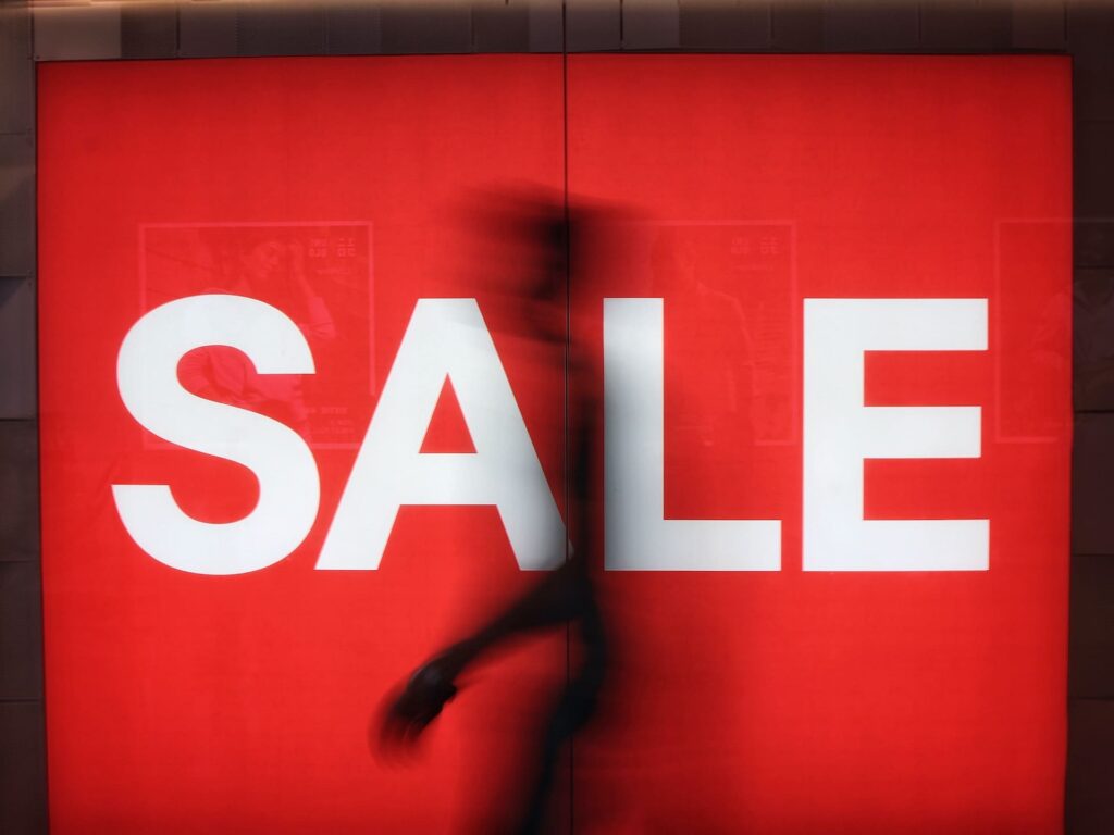 A person passes by a lighted up sale sign