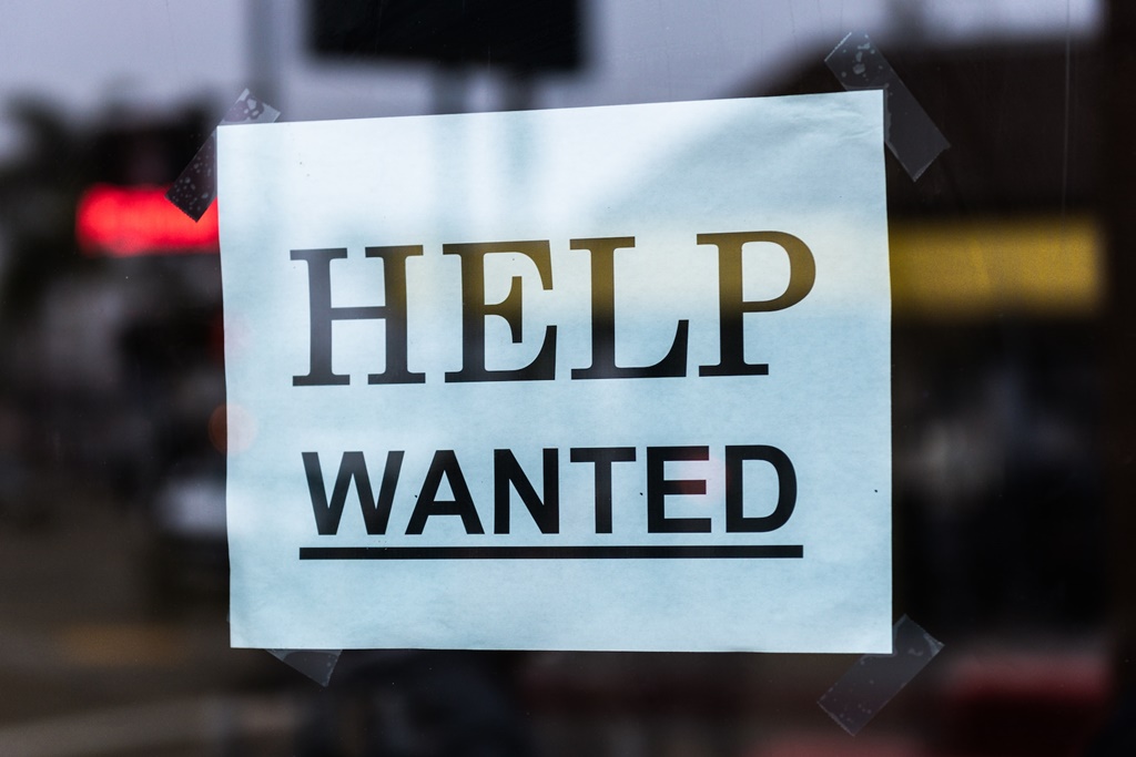 A "Help wanted" sign plastered on a glass door