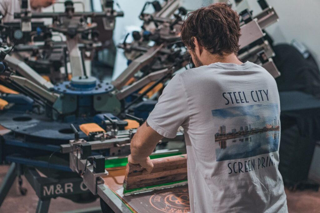 A man operates a screen printing press