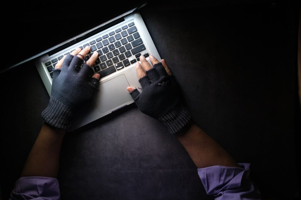 A person wearing fingerless gloves using a laptop